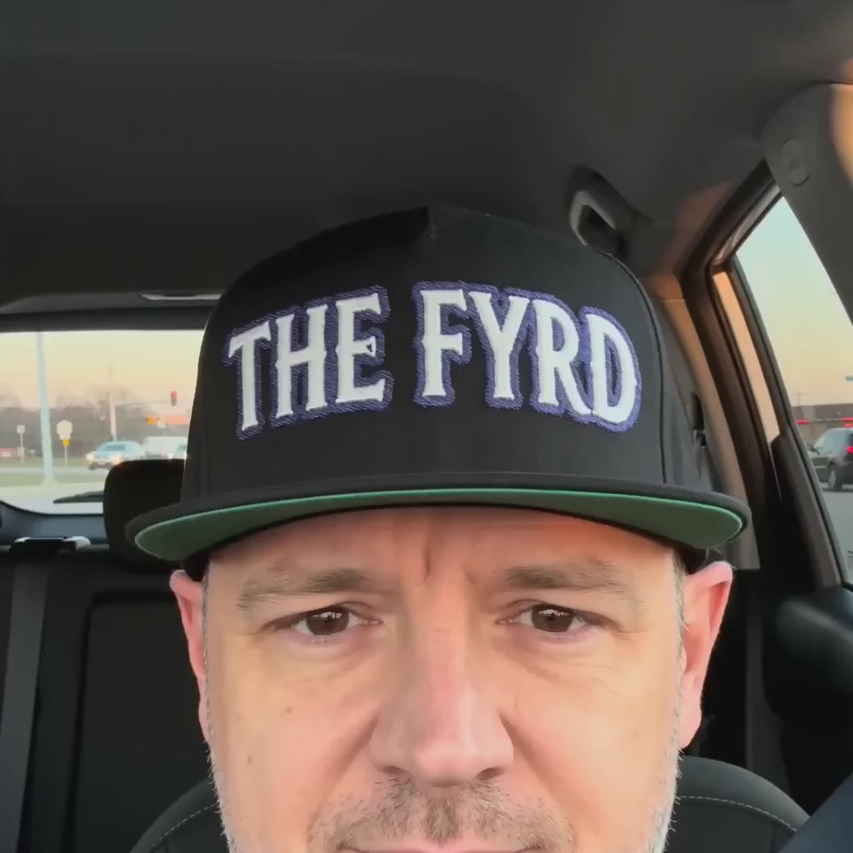 Product video showcasing the black The Fyrd Embroidered Flat Bill Cap with embroidered lettering and a structured flat brim.